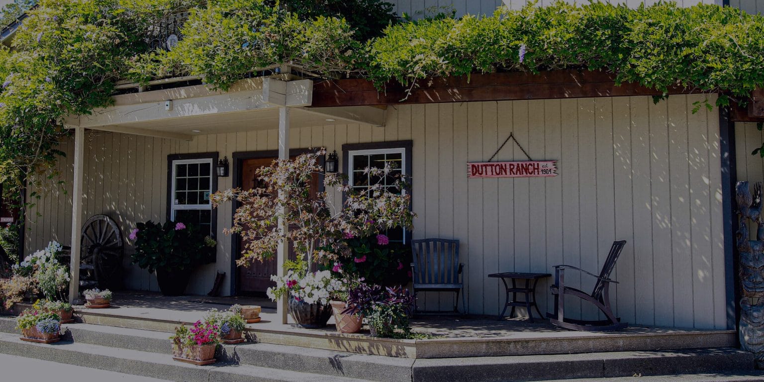 Front of building with greenery growing on top of it and a sign hanging off it that says