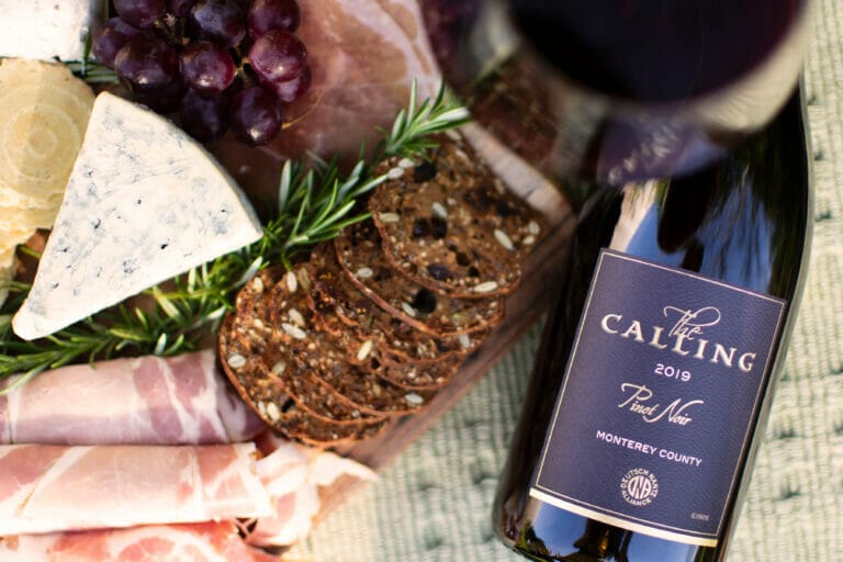 The Calling 2019 Pinot Noir resting beside charcuterie board